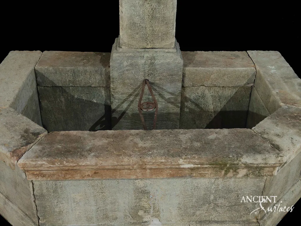 Hand-carved reclaimed limestone wall-fountain trough basin with a wrought-iron overflow bracket around a central pier